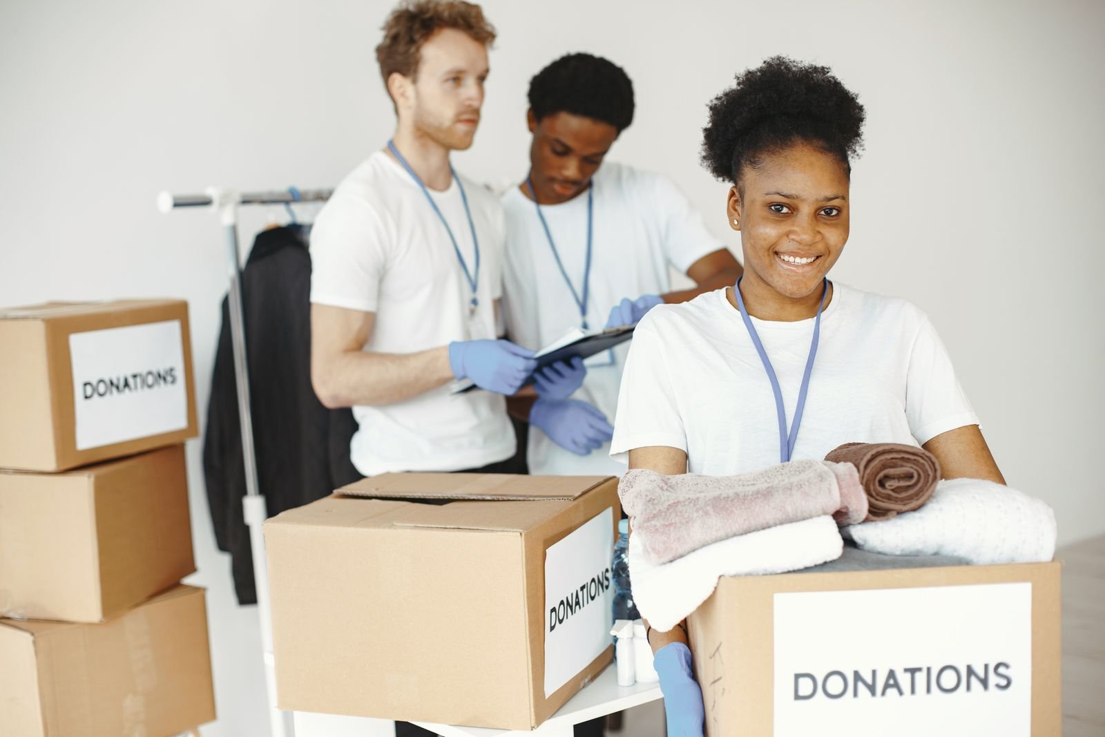 Volunteers smiling while packing boxes of donated clothing marked for donation